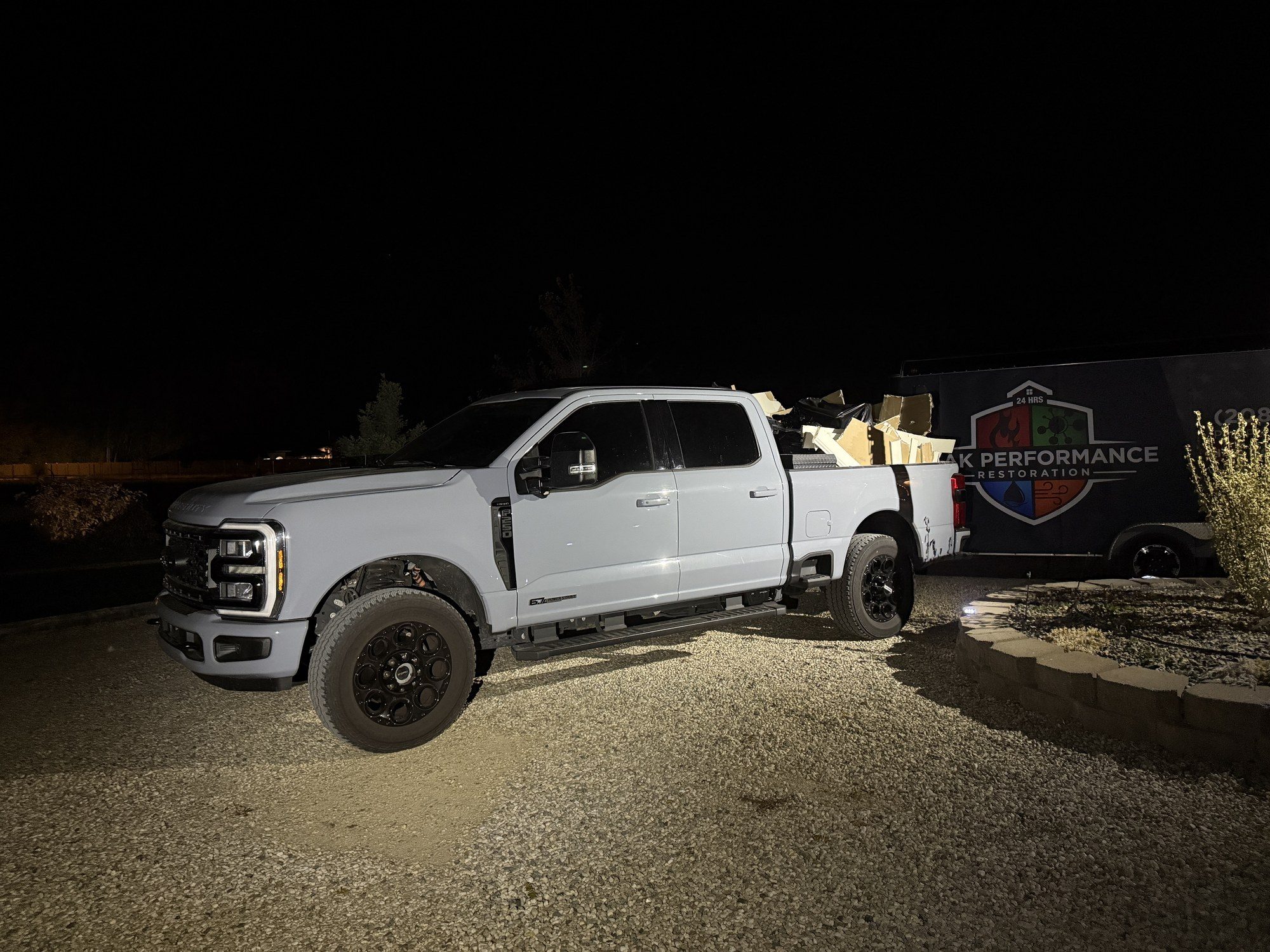 Peak Performance Restoration truck and branded trailer at night on a Treasure Valley job